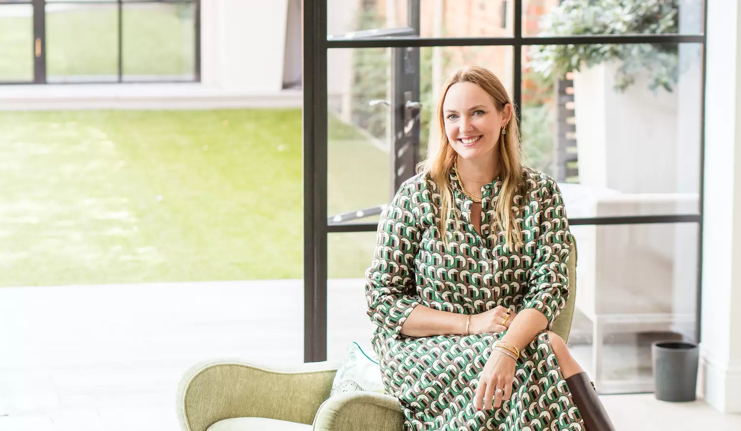 Marisa Hordern, founder of Missoma, smiling at the camera, wearing a green and brown patterned dress.