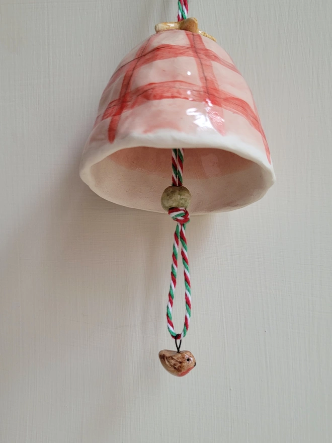 ceramic red and pink check handmade pottery bell with a tiny ceramic robin bead hanging below 
