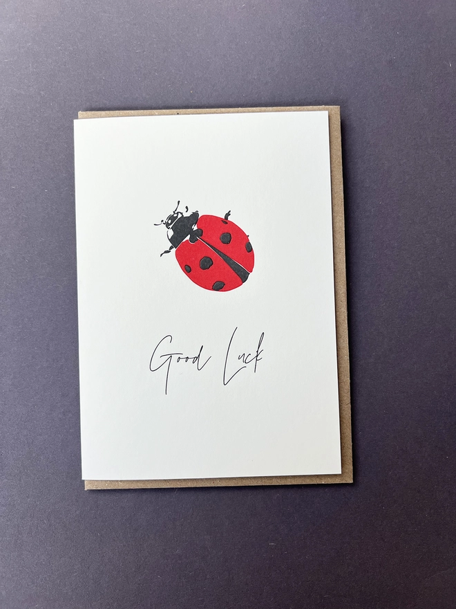 A cute black and Red letterpress Ladybird with "Good Luck" beautifully written in a modern calligraphy underneath.