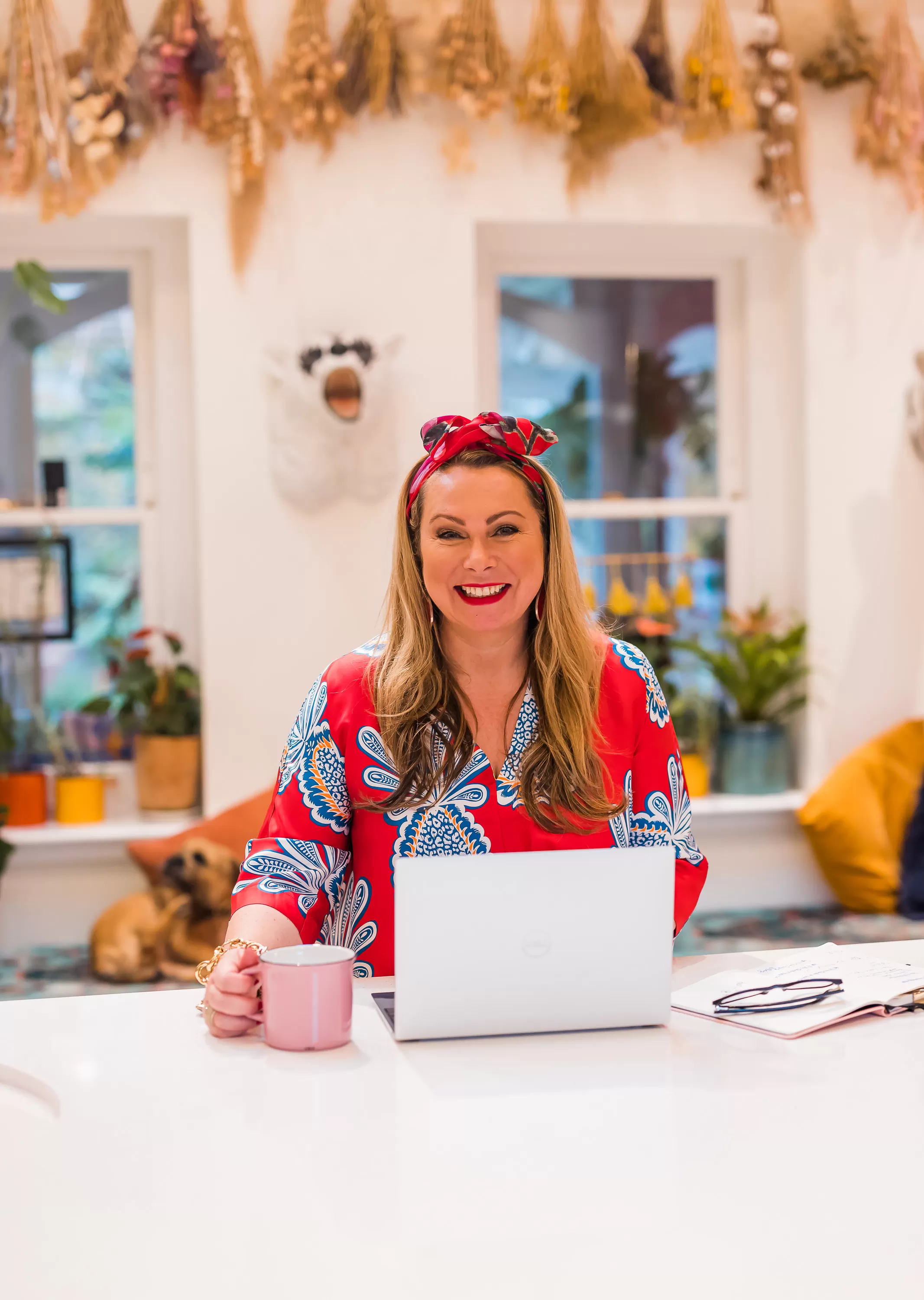 Holly Tucker sat at kitchen table with a laptop wearing a red top