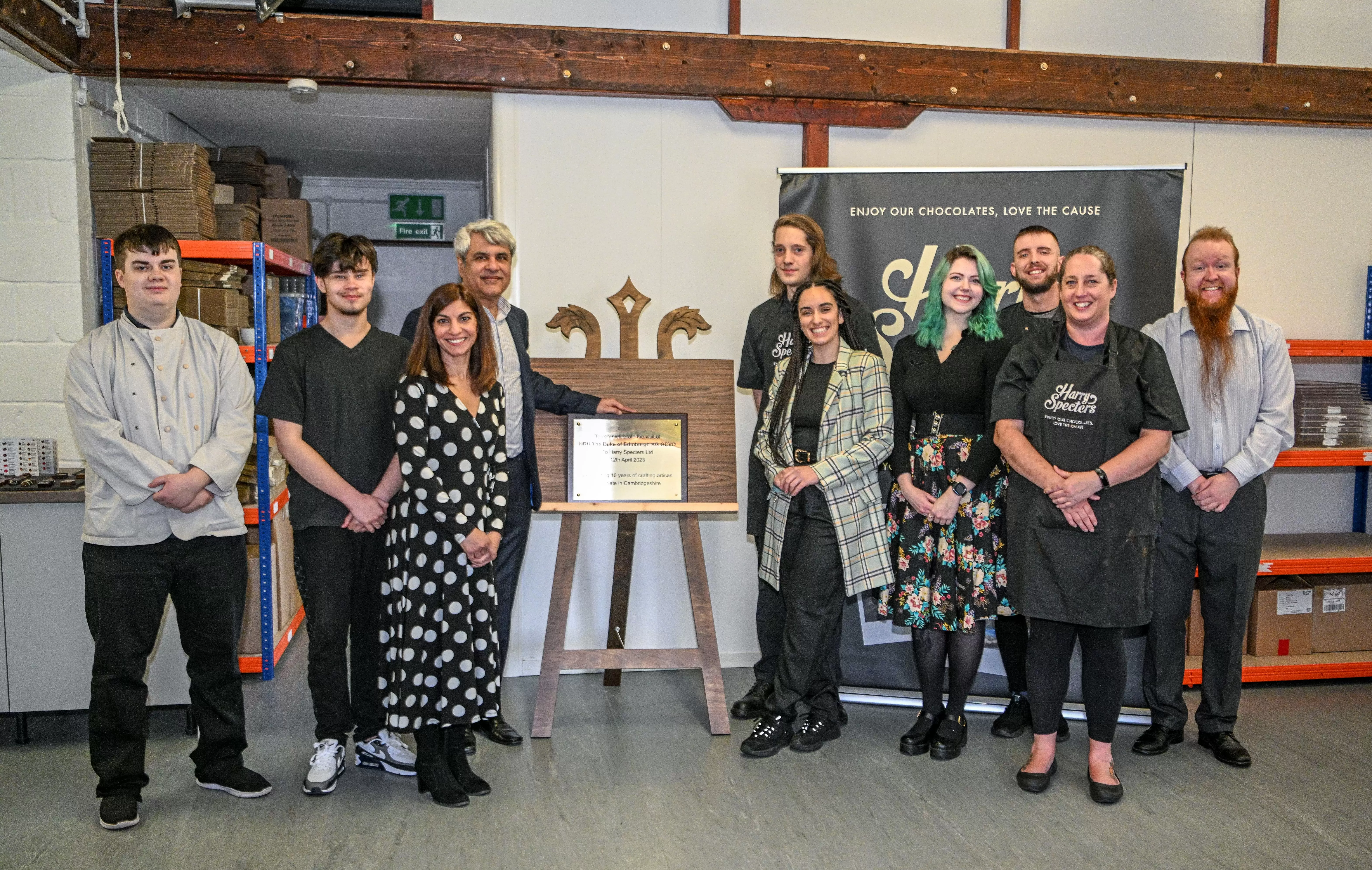 A photo of the Harry Specters team stood around a plaque commemorating a Royal visit from the Duke of Edinburgh