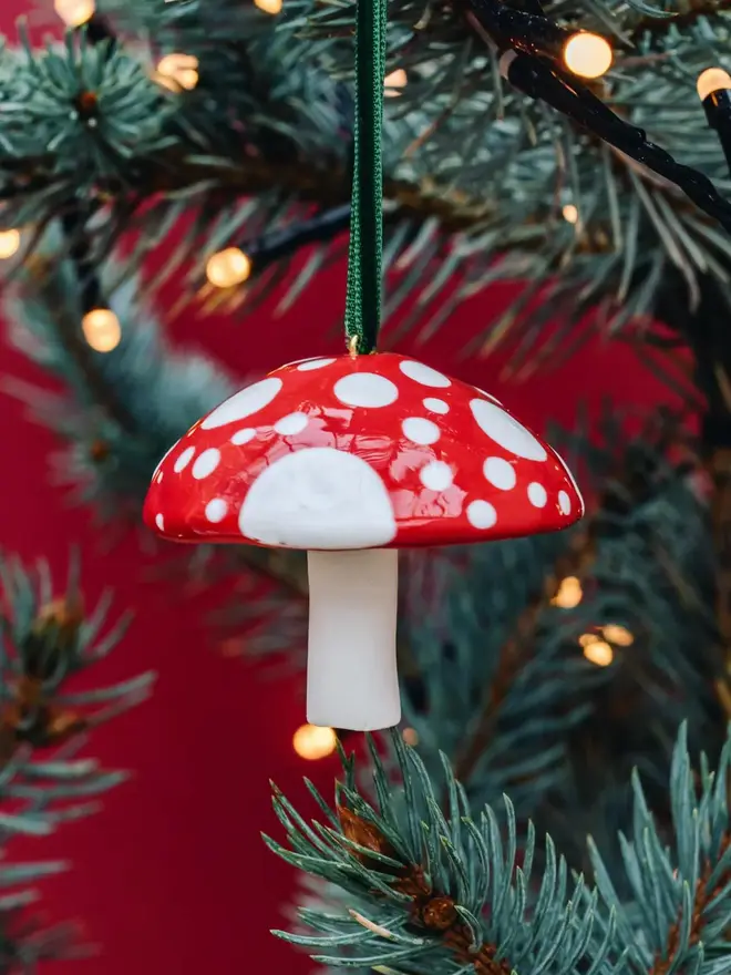 handmade ceramic red and white toadstool bauble on christmas tree