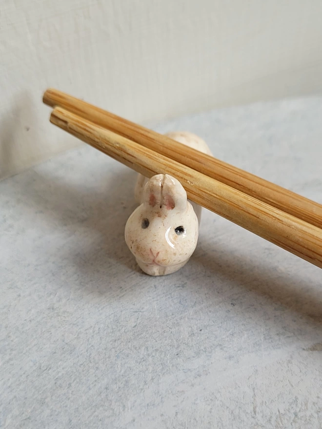 close up of a beige pottery chop stix holder