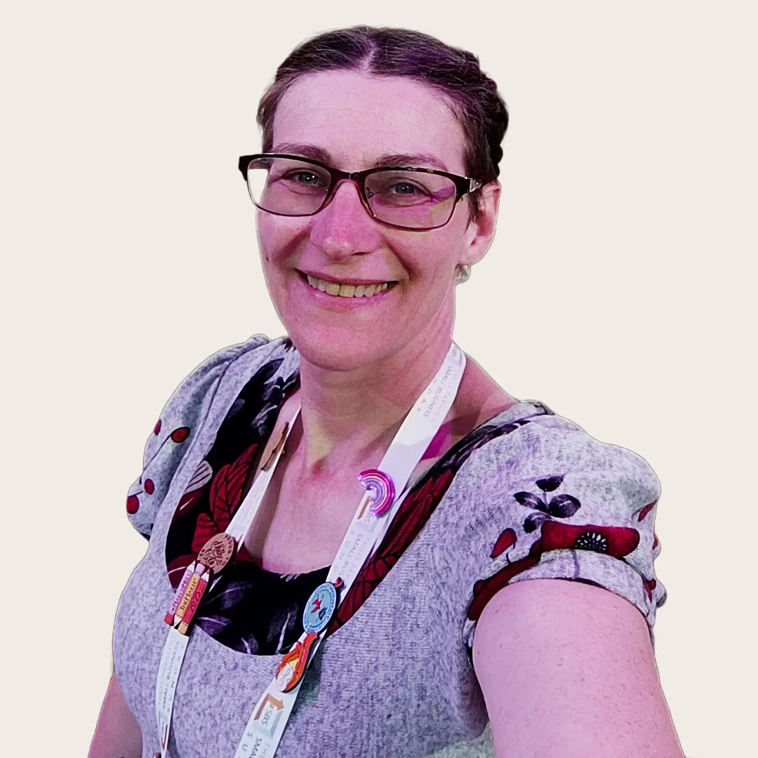 A smiling Scarlet in a floral dress wearing a lanyard of badges that promote shopping with small businesses