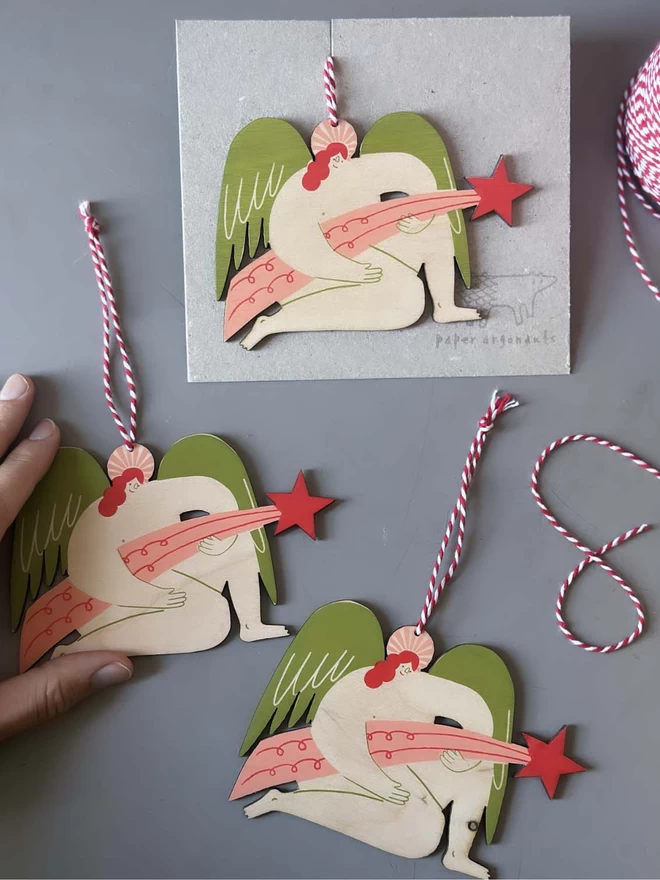 3 wooden angel decorations are shown, being packaged up with string