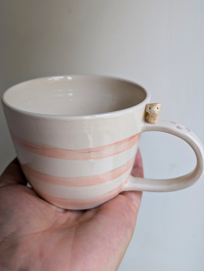 pottery cup with pink stripes and a tiny ceramic cat on the handle