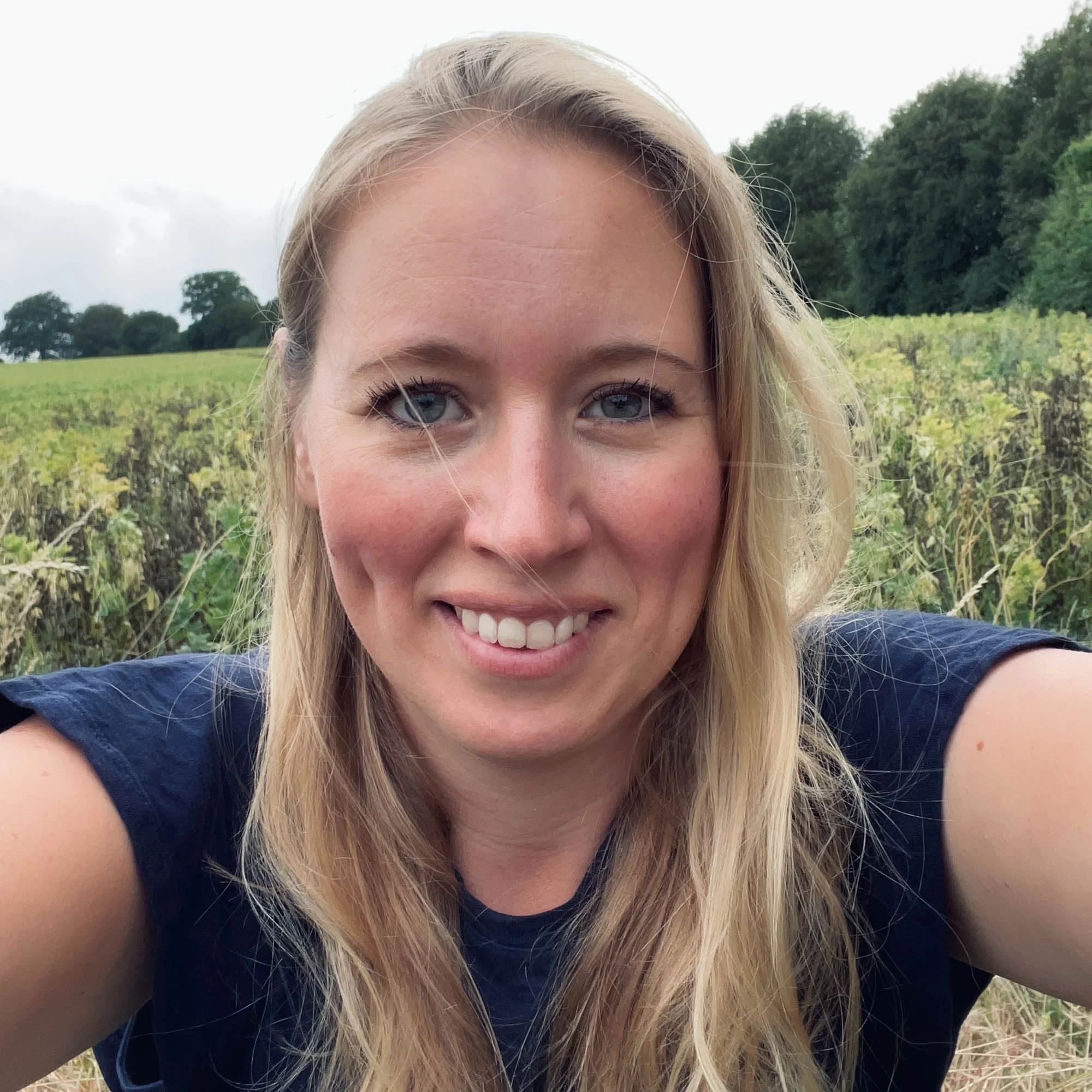 A portrait photograph of Lucy Miller with a field as a backdrop.