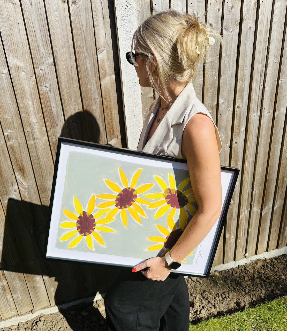 Person holding sunflower painting