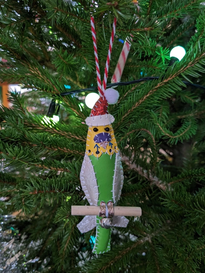 A green and yellow hand stitched faux leather budgie Christmas decoration wearing a glittery Santa hats