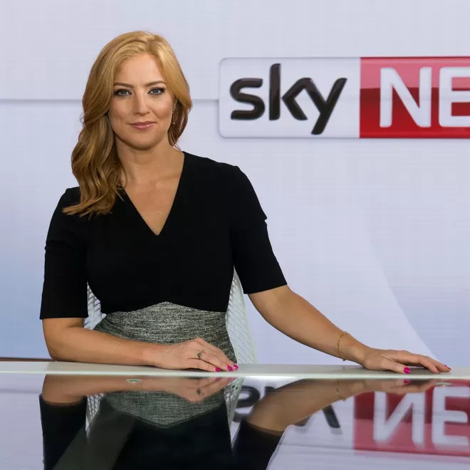Sarah Jane Mee sitting at the news desk with Sky news logo backgdrop