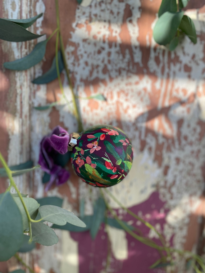 hand painted Christmas bauble deep purple background adorned with twizzle coral flowers