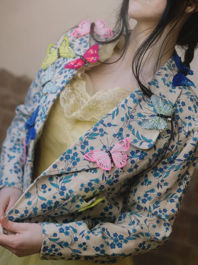 Butterfly clips on a vintage floral jacket worn by dark hair model.