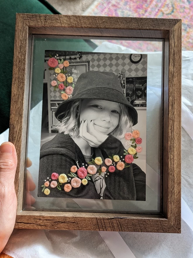 B&W photo of girl with pastel flowers embroidered around her in frame