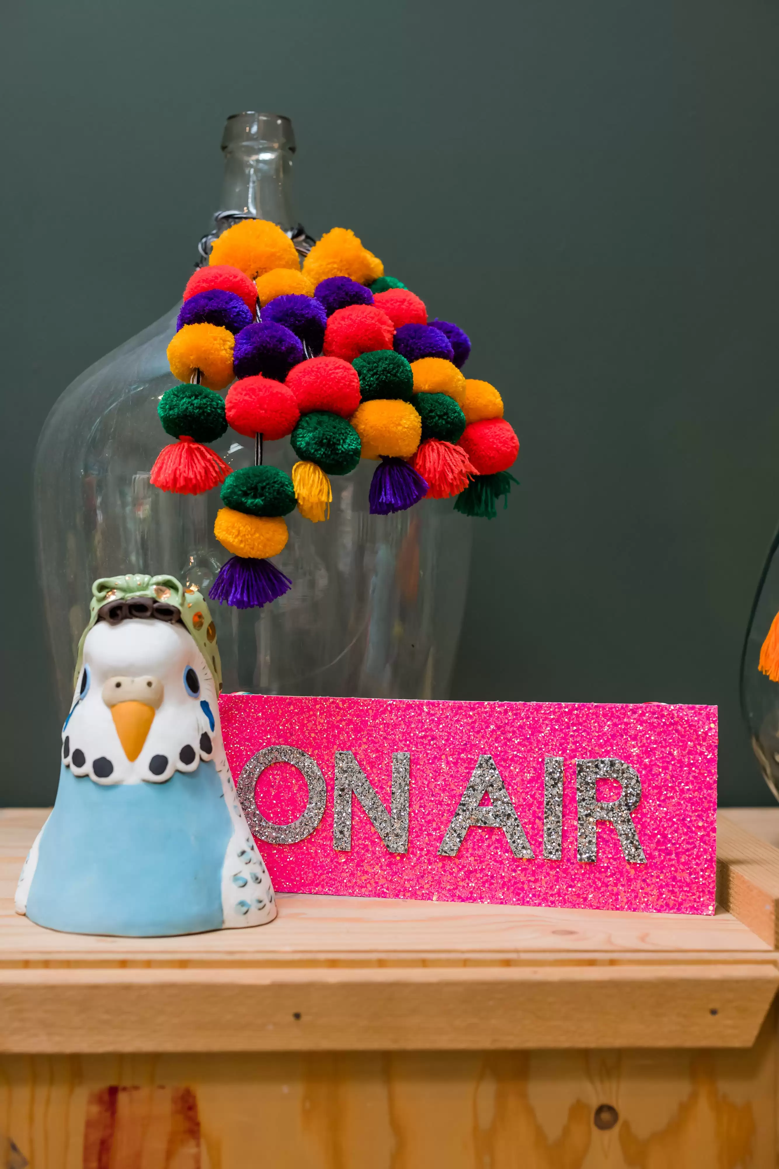 On air sign in silver glitter next to a ceramic bird on a wooden table 