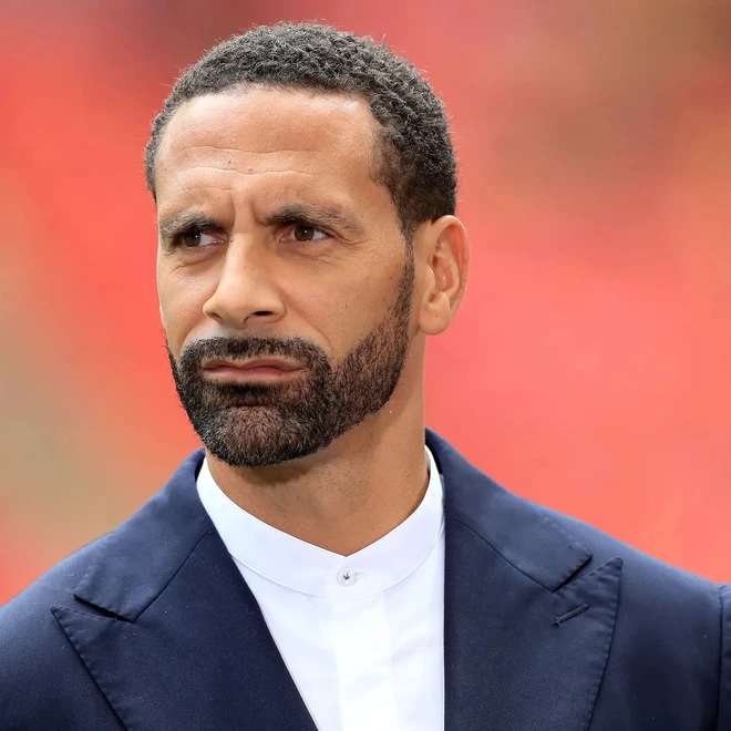 Rio Ferdinand OBE, Sportsman, Broadcaster, Campaigner, looking into the distance, wearing a suit.