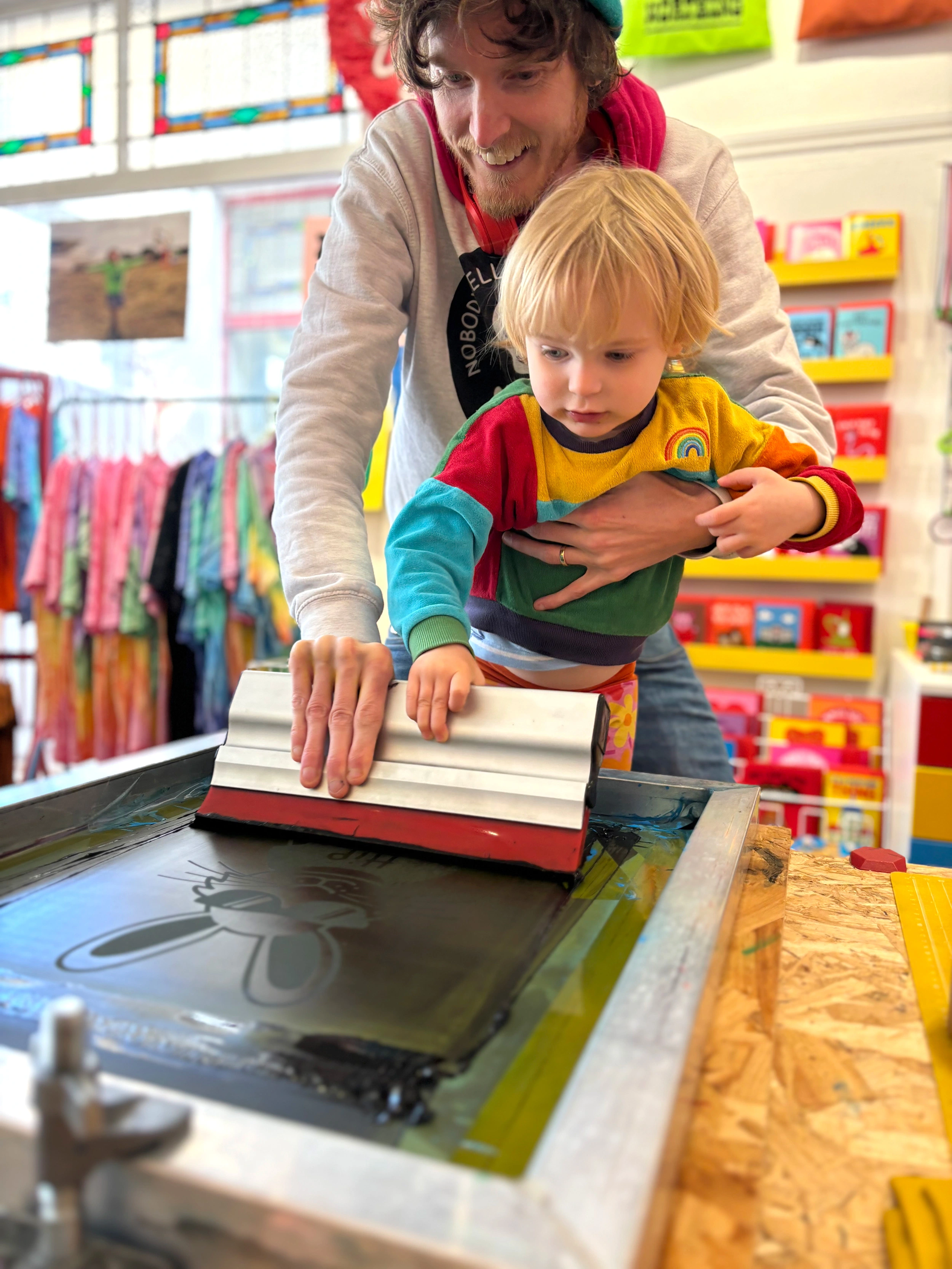 Jam from hello DODO Kids is screen printing whilst holding his 2 year old son who is also helping!