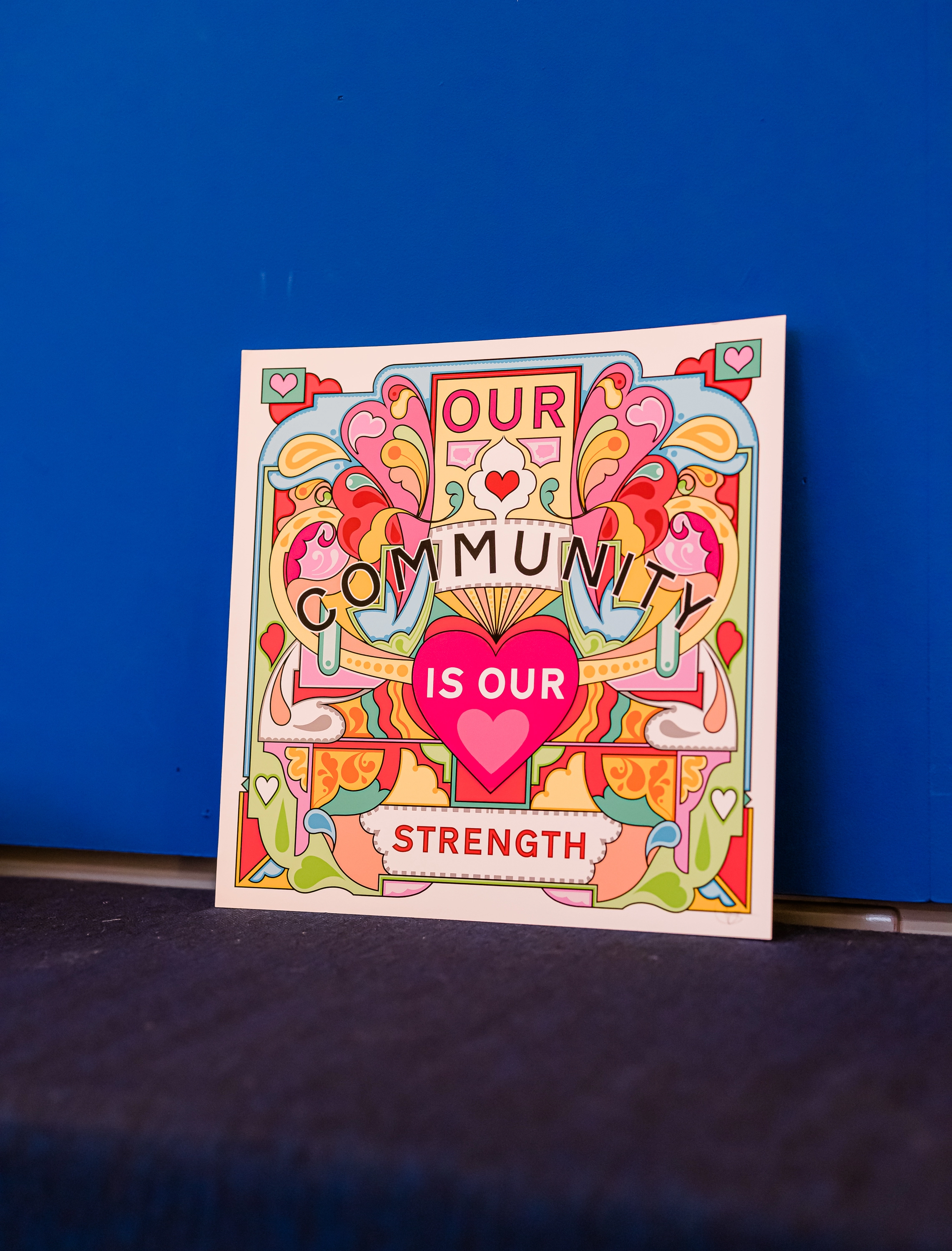 Print by Rebecca Strickson that says 'our community is in our strength'