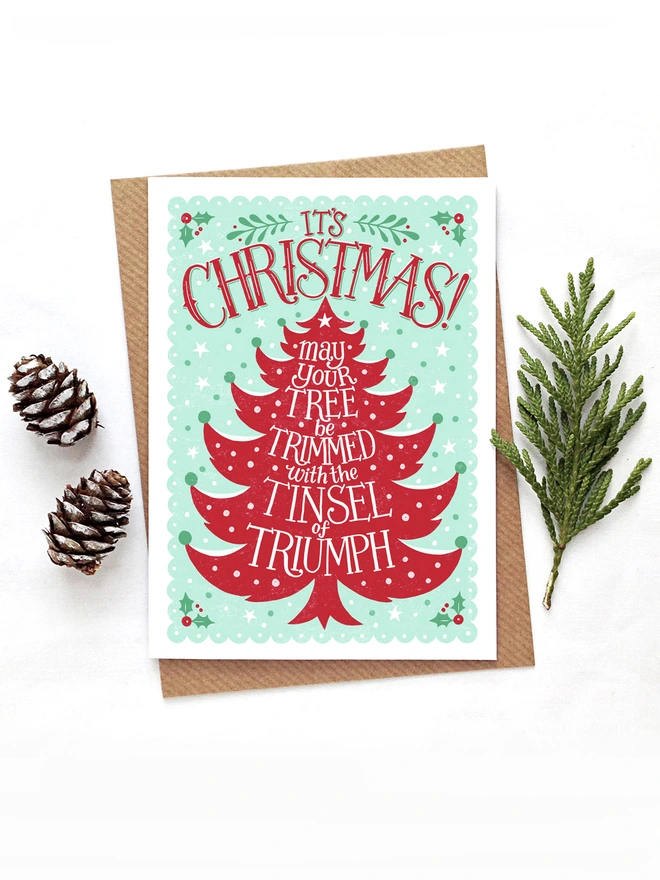 red and green christmas tree card with pine cones and leaf