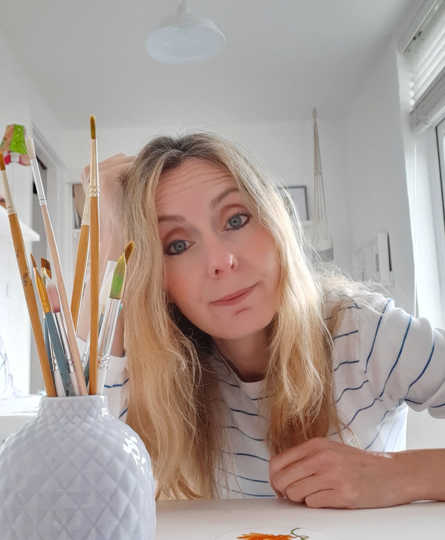 a photograph of an illustrator in her studio with a pot of brushes