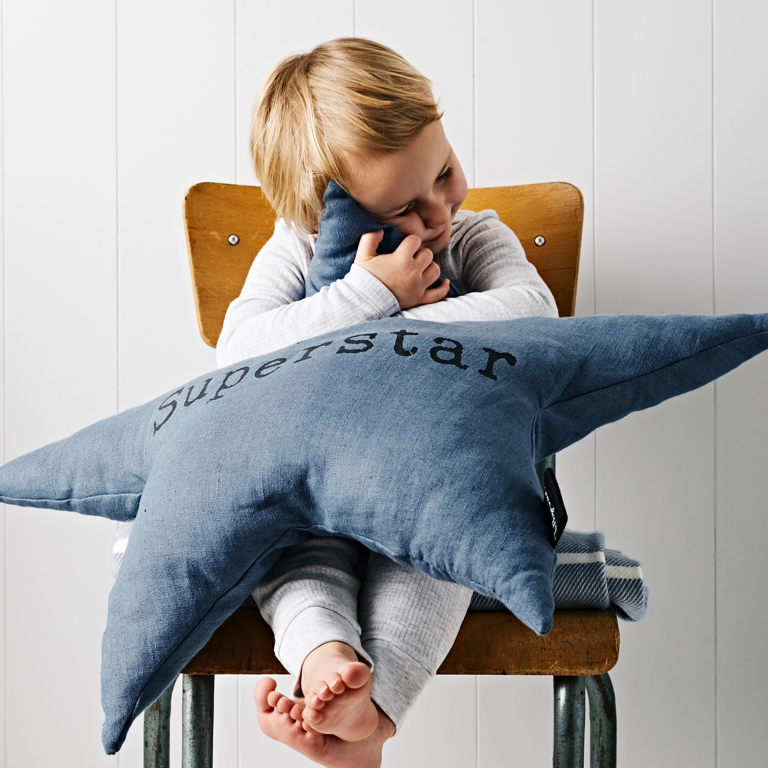Child hugging large star shaped cushion with the text 'superstar' printed