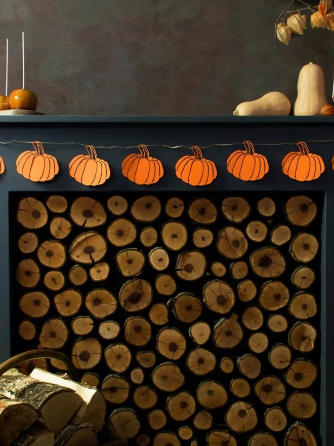 Orange pumpkin garland displayed on black mantelpiece above fireplace