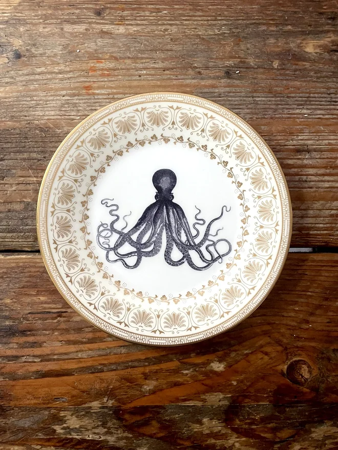 vintage plate with an ornate border, with a printed vintage illustration of an octopus in the middle 