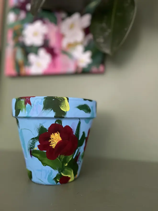 vibrant hand painted interior turquoise floral plant pot deep red camellia flowers.