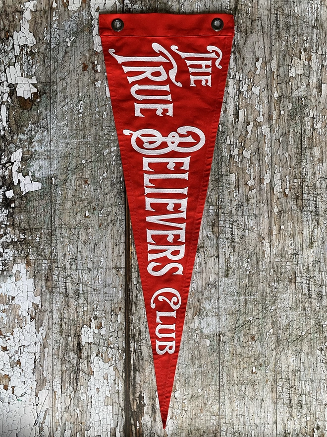 A red pennant flag with the words The True Believers Club