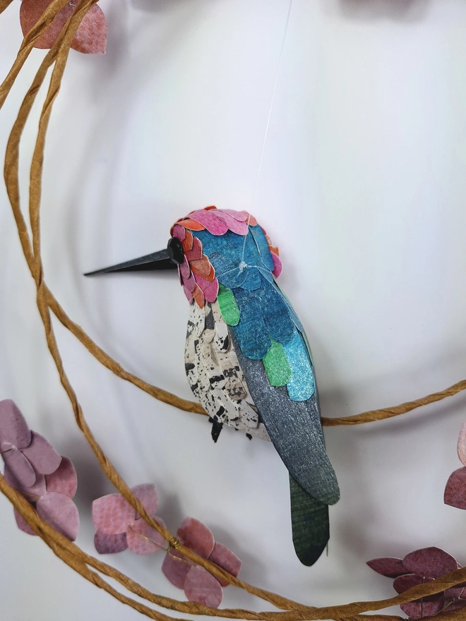 back view of an Anna's hummingbird sculpture, made from handprinted papers