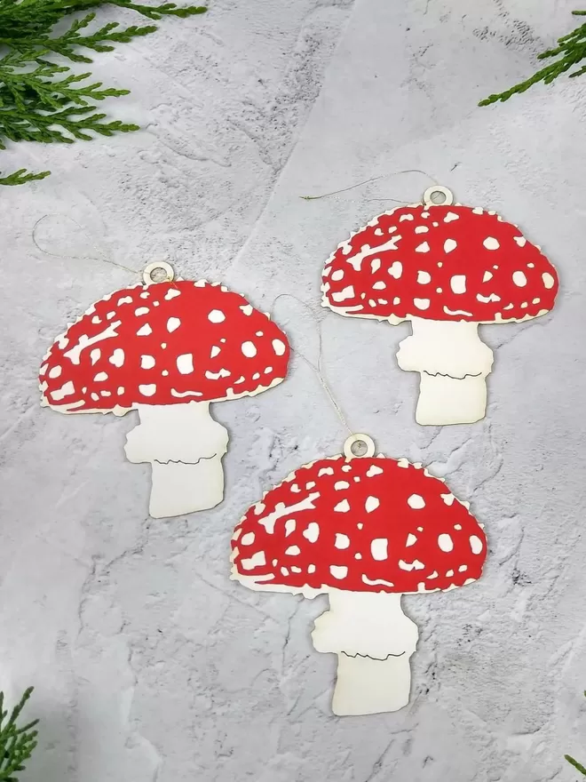 3 bright red and white paper mushroom ornaments threaded with gold hanging loop.