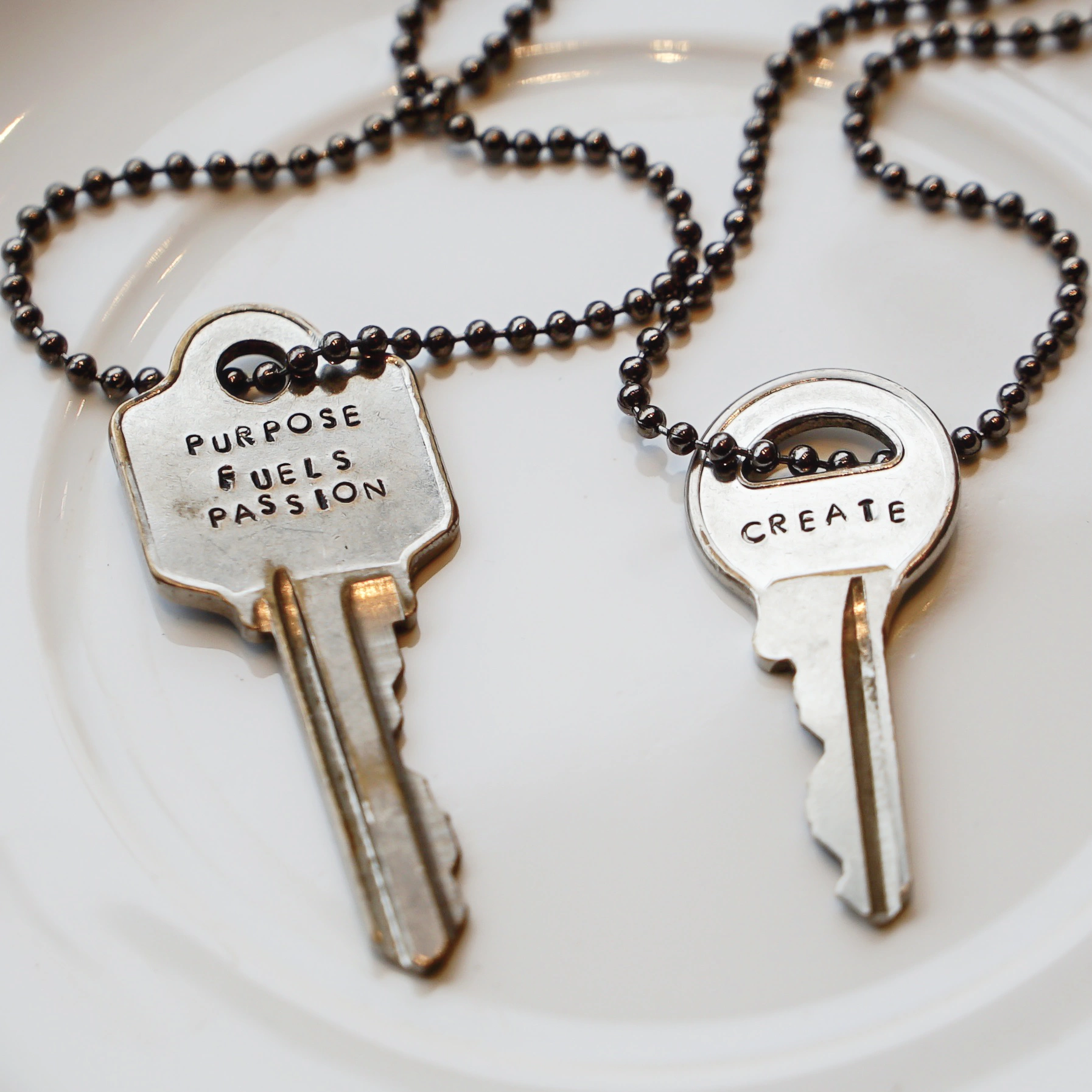 Two keys on a white plate with the words purpose fuels passion and create on them 