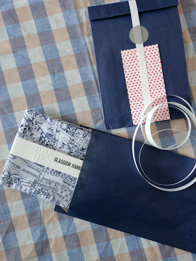 Mr.PS Glasgow Handkerchief with optional gift wrapping of navy paper, ribbon and gift card on a gingham tablecloth