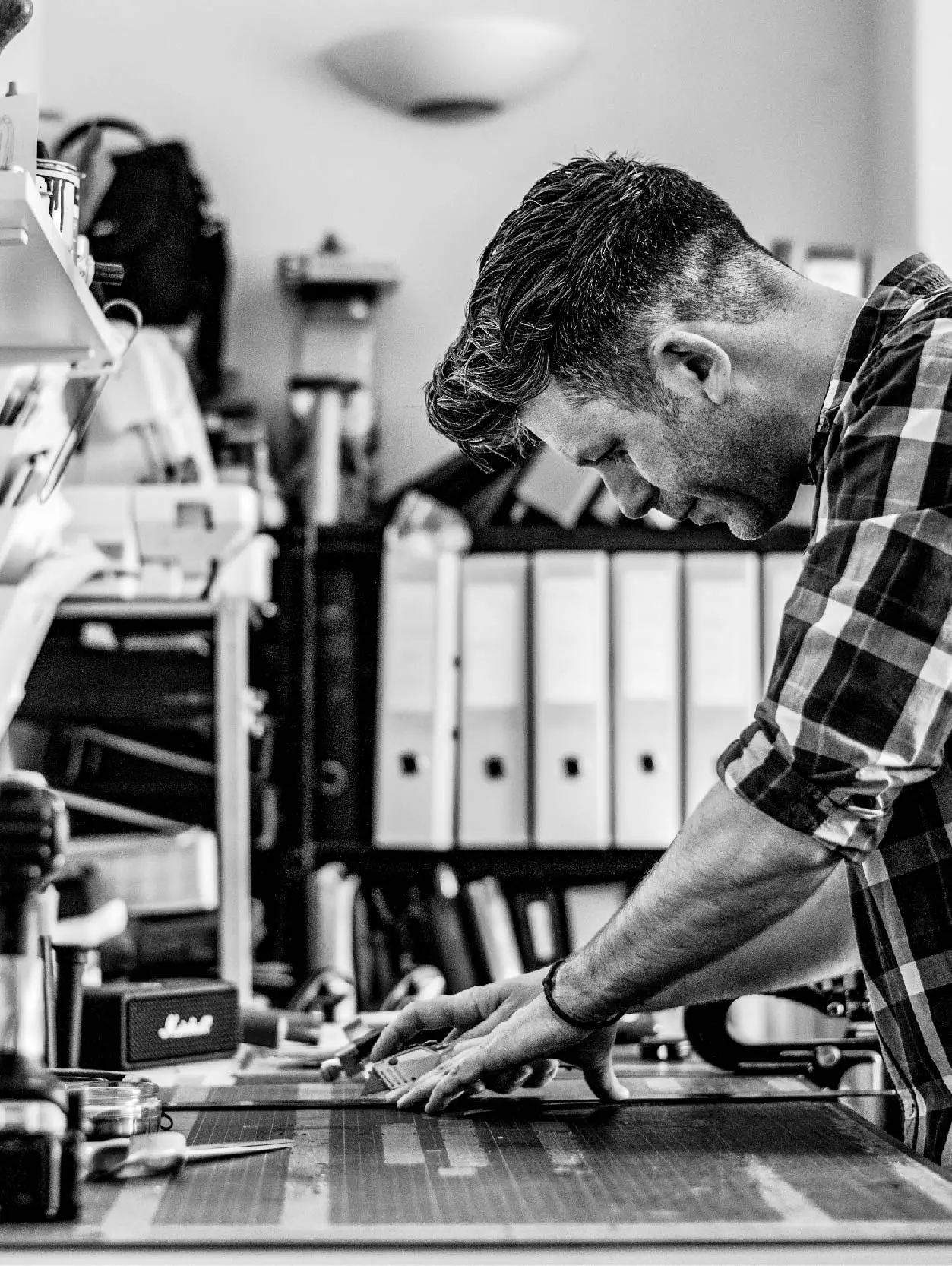 Ben working in the studio cutting a pattern and wearing a check shirt.