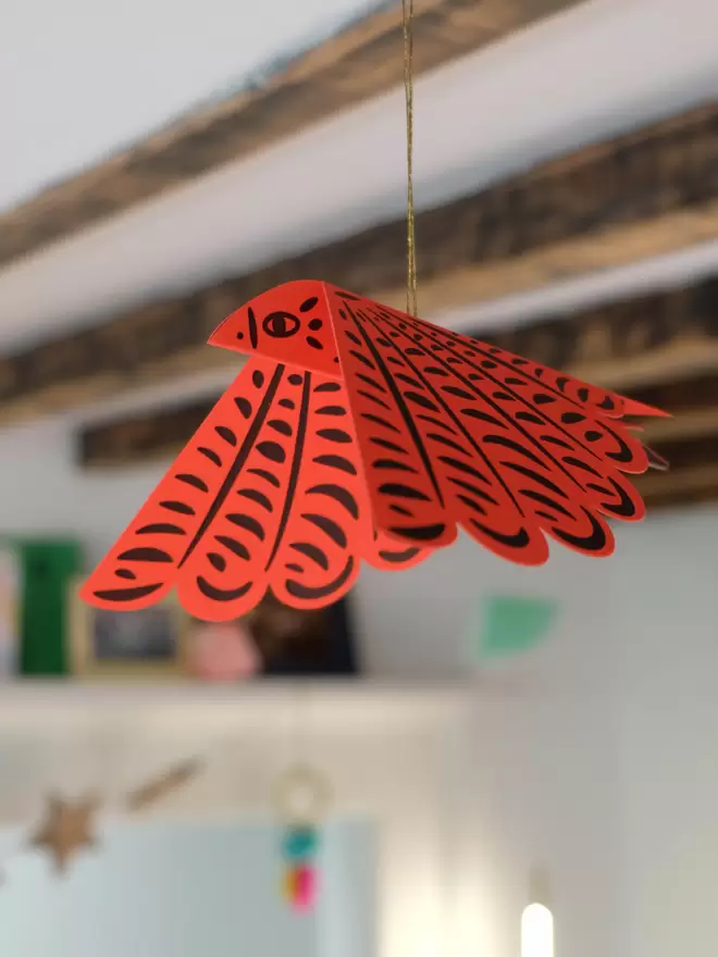 Electric red letterpress bird hanging from gold thread.