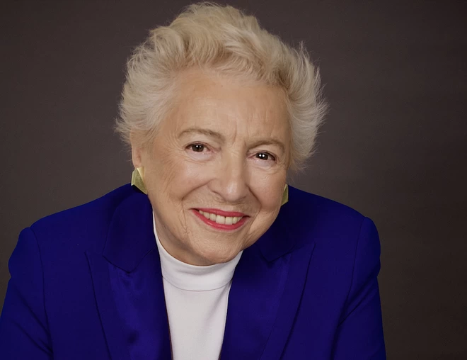 Dame Stephanie "Steve" Shirley CH, Tech Pioneer, Businesswoman and Philanthropist, smiling at the camera, wearing a blue suit jacket.