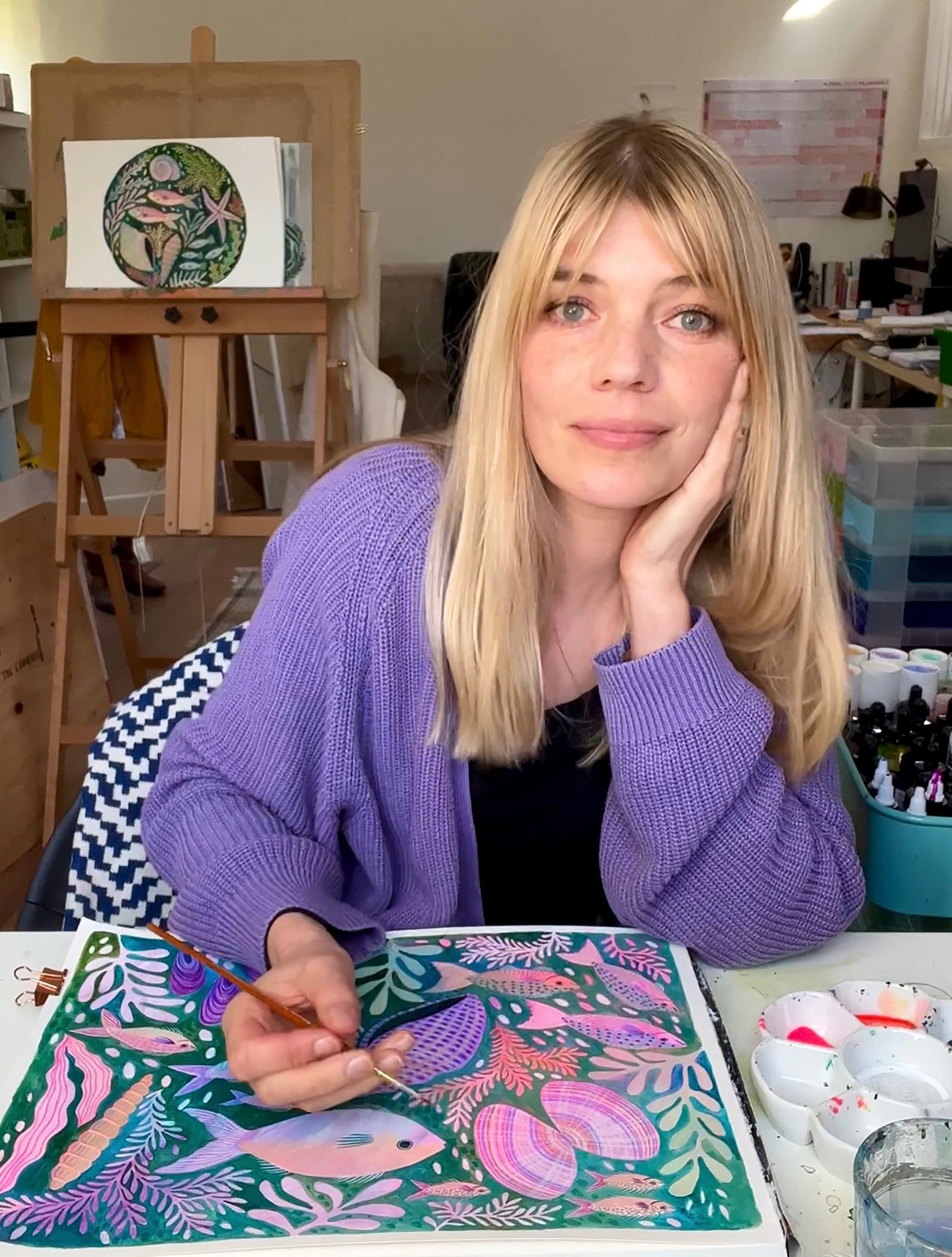 Artist Lee Foster-Wilson in her studio painting a picture of fish