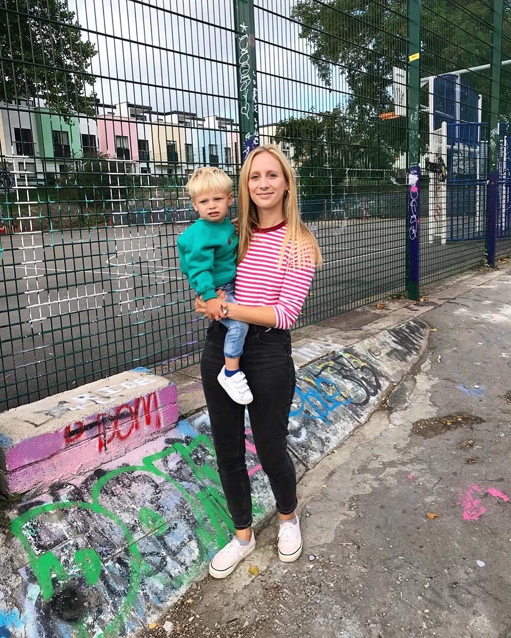 A blonde woman holding a small blonde child in a skatepark