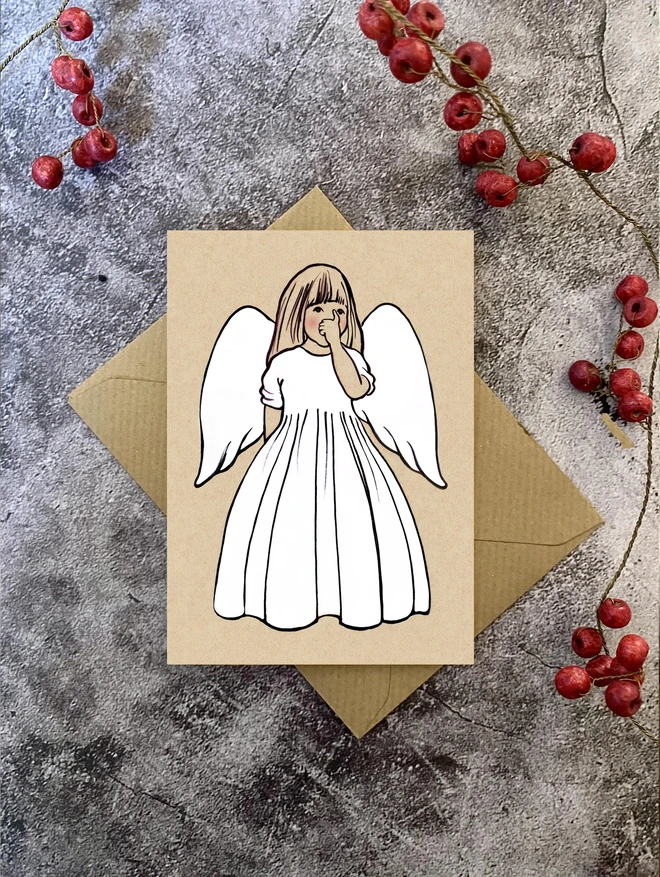 greeting card of an angel with long fair hair sucking her thumb laid on a Kraft envelope