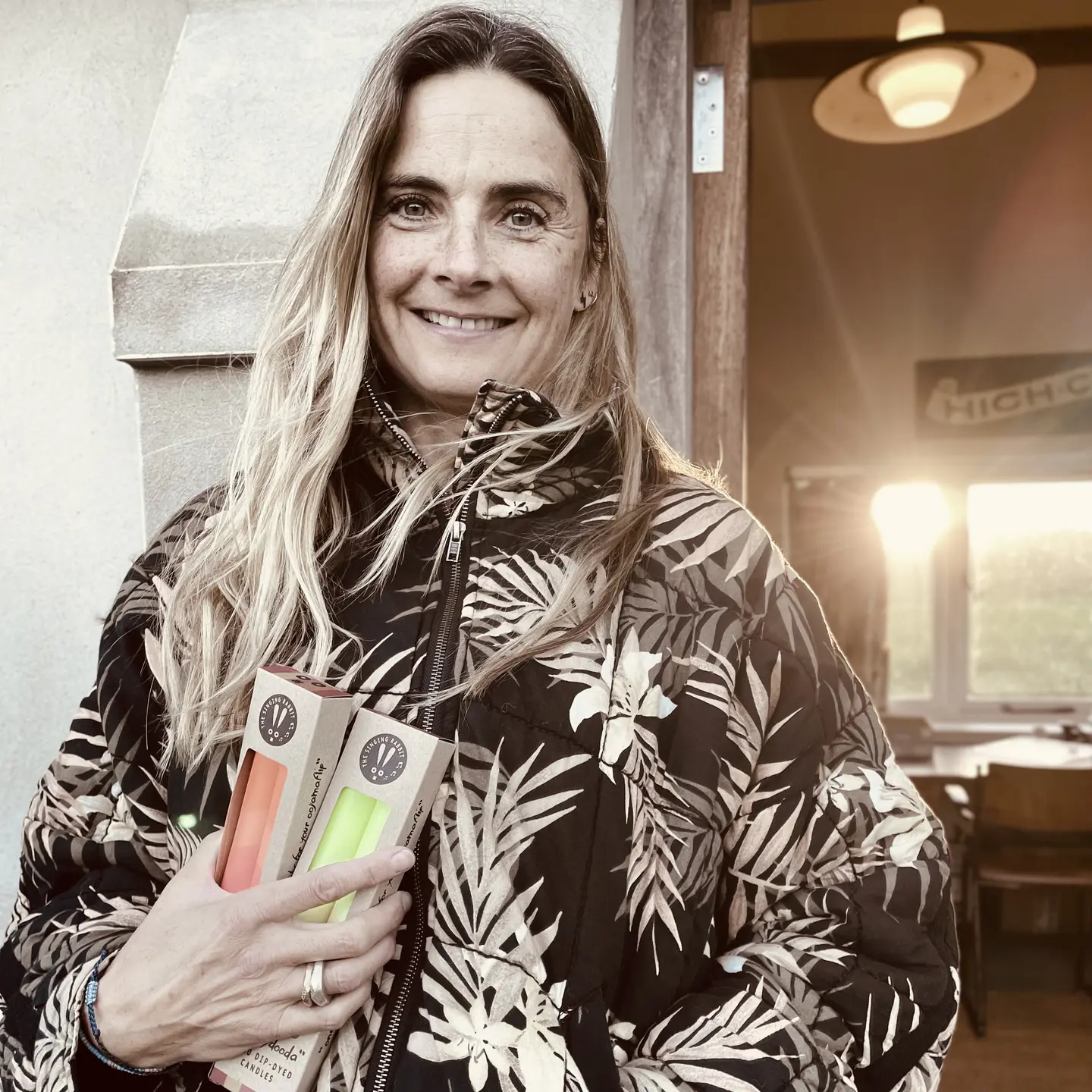 Image of The Singing Rabbit founder Vanessa holding her hand dip dyed candles outside her studio.