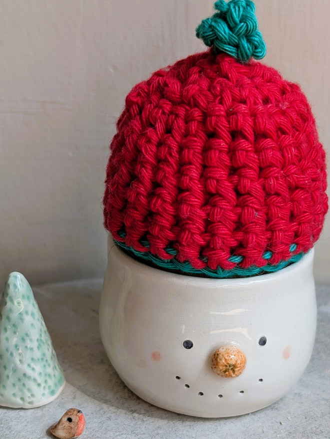 snowman ceramic egg cup with a tangerine nose and red woolly hat