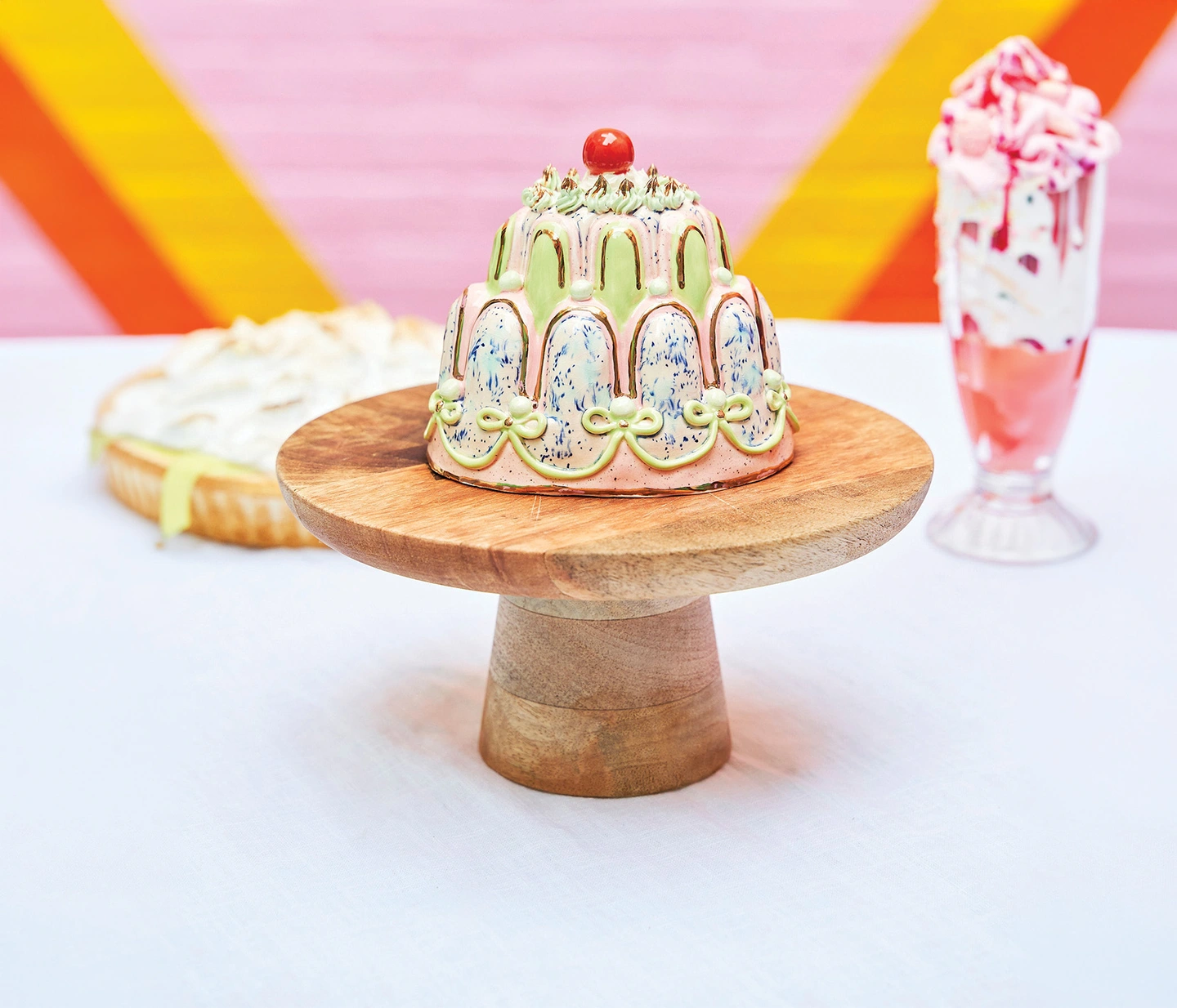 Ceramic cake sculpture on a wooden cake stand
