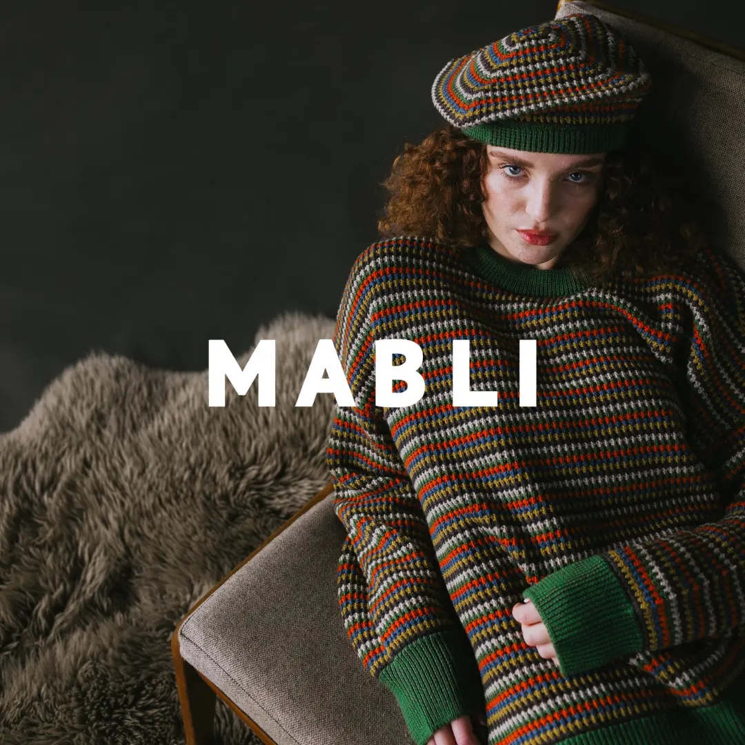 Model in MABLI's AW24 Porth Pullover and Tam in 'Monstera,' featuring bold, colourful patterns inspired by Welsh blanket tapestry.