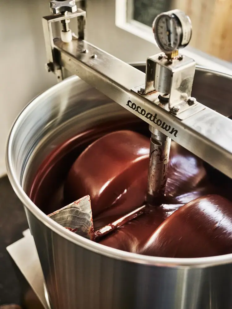 liquid chocolate being mixed in silver machinery