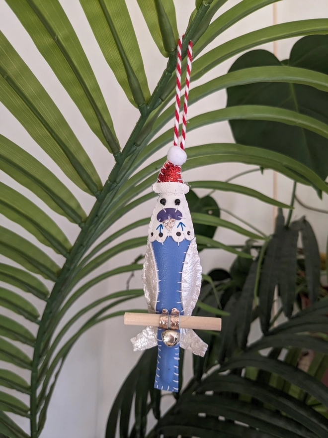 A blue hand stitched faux leather budgie Christmas decoration wearing a glittery Santa hat