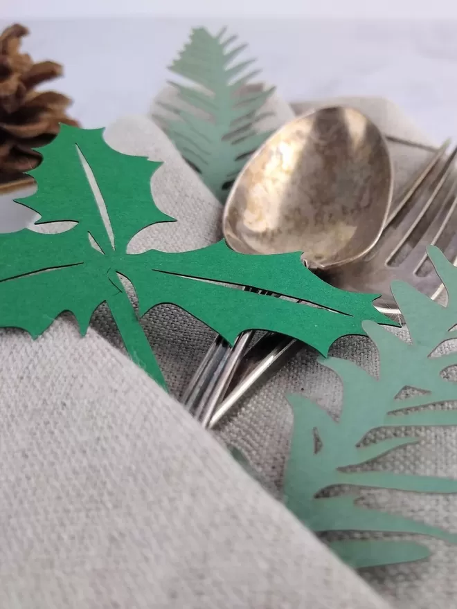 Closeup of folded napkin with cutlery and paper spruce and holly decorations