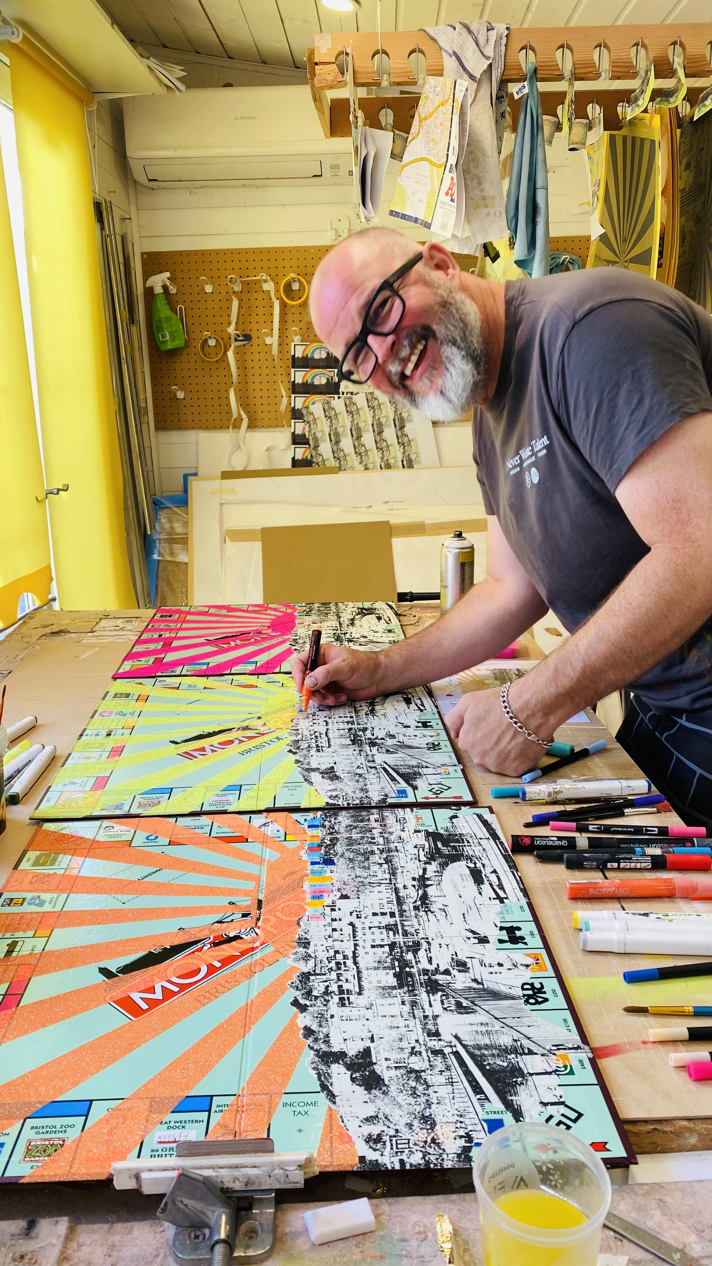Man wearing glasses smiling while signing his artwork
