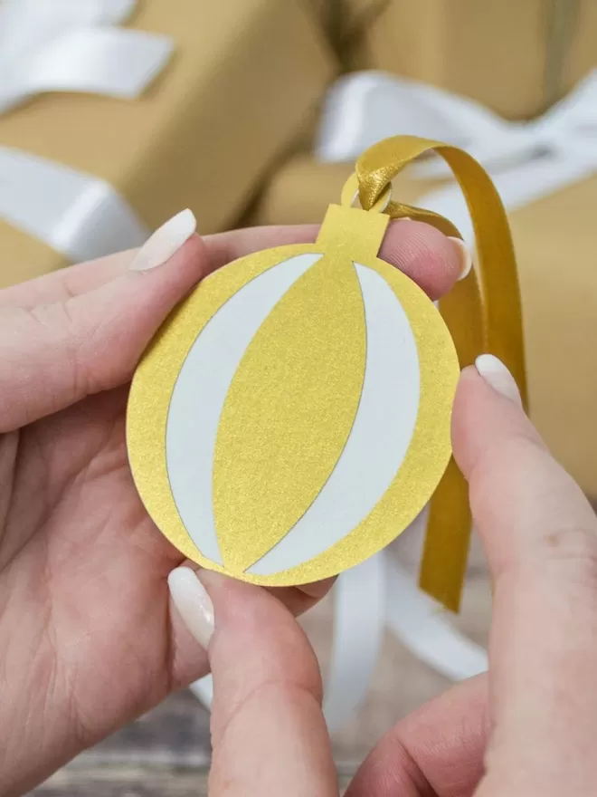 Model holds gift tag with gold ribbon.Gold Christmas Ornament Gift Tags