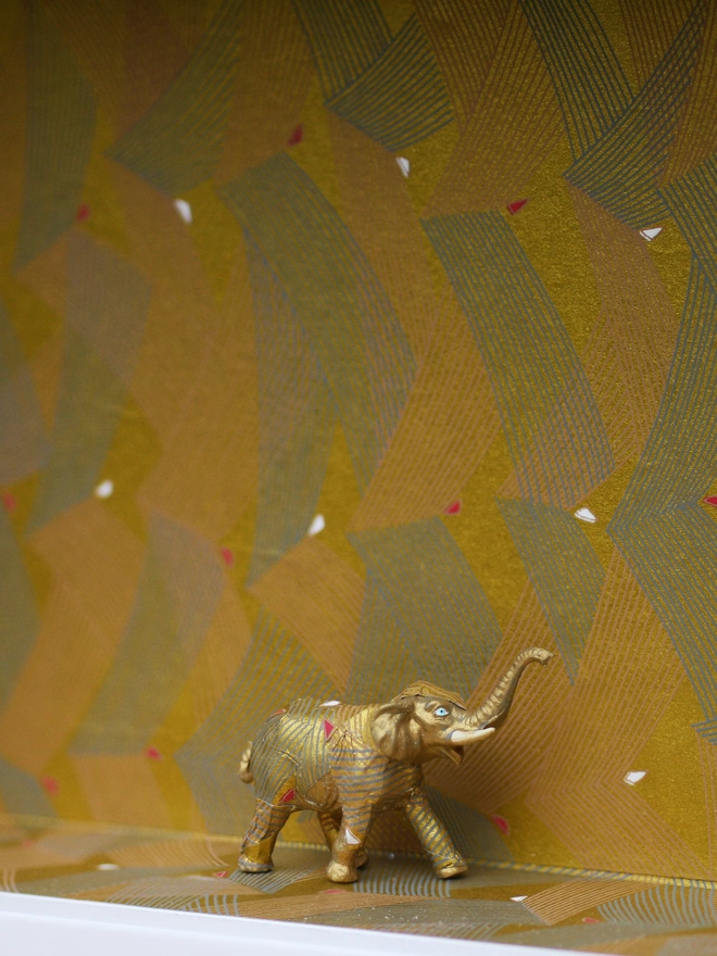 Miniature elephant blending seamlessly into a beautifully wallpapered wall