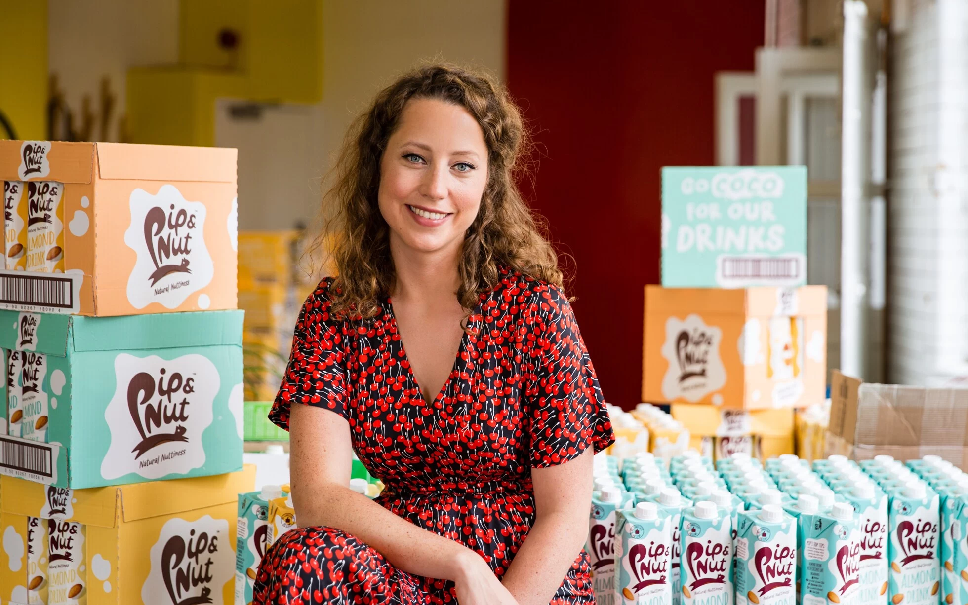 Pippa Murray, founder of Pip and Nut, smiling at the camera in a red cherry dress.