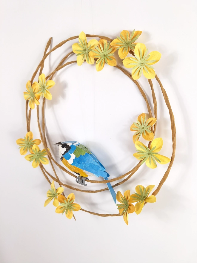 side view of a soring wreath featuring yellow flowers and a handmade blue tit sculpture